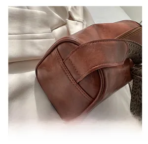 Detail of vintage brown cylinder bag showing leather grain and jacquard strap stitching