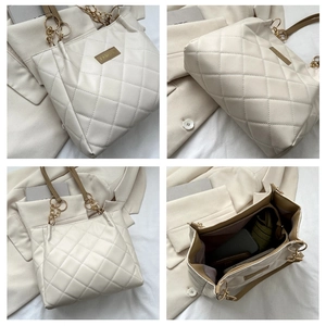 Detail view of large quilted tote bag in cream white with brown strap and gold chain