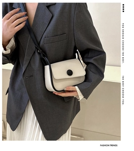 Fashionable cream white saddle bag with black contrast piping and crossbody strap details