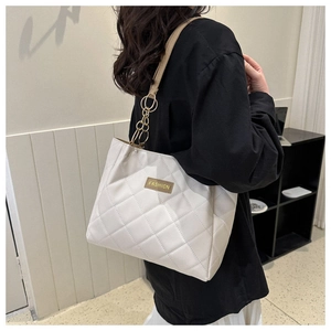 Close-up of beige quilted tote bag with fashion label and golden metal hardware details