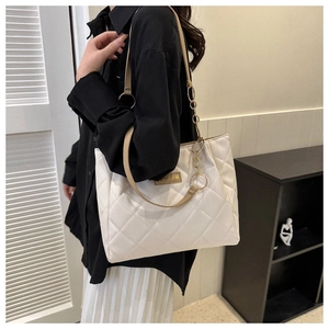 Detail of white quilted rhombus pattern on large tote bag with golden chain and leather strap