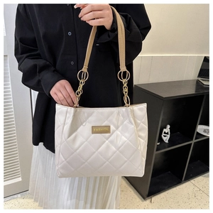 Detail of white quilted tote bag with golden metal chain strap and luxury leather texture