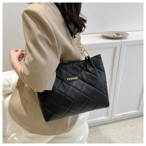 Detail of black quilted tote bag featuring golden chain strap and fashion label on PU leather