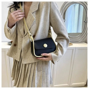 Detail of vintage contrast color saddle bag with large round buckle on a model
