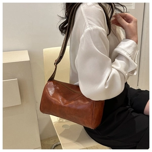 Detail of vintage caramel cylinder bag featuring wide geometric jacquard strap on model