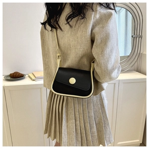 Detail of a vintage contrast saddle bag featuring black leather with cream edge piping
