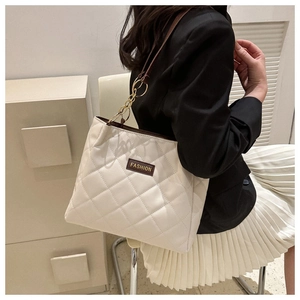 Detail of cream quilted tote bag with chain strap and fashion label on the leather