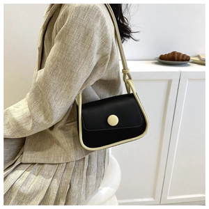 Detail of a color-block crossbody bag in black and beige on a stylish model outfit