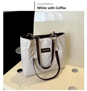 Detail of white quilted tote bag with coffee straps and gold chain link accents
