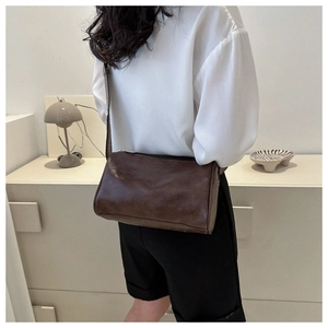 Detailed view of a vintage brown cylindrical shoulder bag with fine leather texture