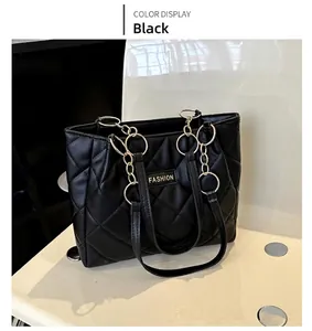 Detail of black quilted tote bag with gold ring chain handle and fashion label
