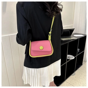 Detail of a bright pink crossbody bag with neon green accents shown on a model