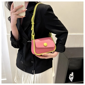 Detail of a pink and neon green colorblock crossbody bag worn with a black blazer