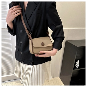Model wearing a vintage khaki saddle bag with brown trim and adjustable strap