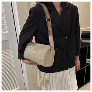 Borsa cilindrica beige con tracolla vintage a motivi indossata da una modella