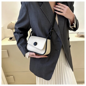 Model showing a beige and black contrast saddle bag paired with a grey blazer outfit