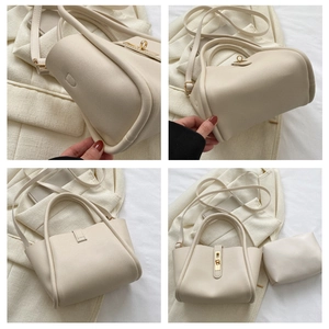 Detailweergave van crème emmertas met goudkleurige sluiting en bijpassende kleine pouch