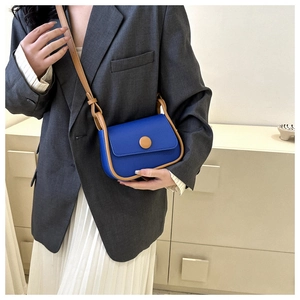 Klein blue and brown crossbody saddle bag shown on a model with a grey blazer