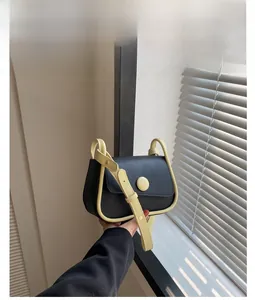 Detail of minimalist black crossbody bag with cream contrast trim and round yellow buckle