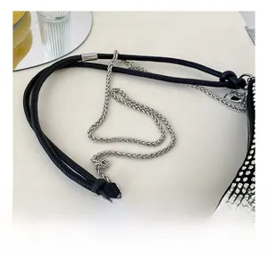 Detail of rhinestone shoulder bag showing silver metal chain and braided black straps