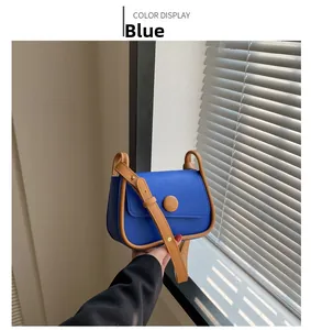 Detail view of a vintage blue saddle bag with brown trim and adjustable strap