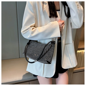 Detailed view of black rhinestone handbag with silver chain on a white suit jacket