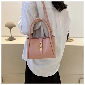 Lifestyle-weergave van een lichtroze crossbody-tas met gouden draaislot op model