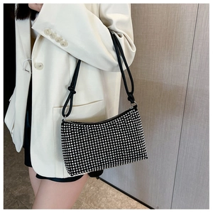 Detail of black rhinestone shoulder bag with silver crystals on white suit model