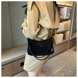 Detail of a black rhinestone shoulder bag with metal chain strap and elegant leather handle