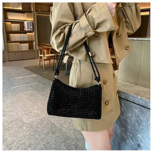 Detail of black rhinestone shoulder bag with elegant double knotted straps on beige coat
