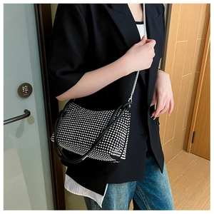 Detail of a sparkling black rhinestone crossbody bag with silver chain strap and leather handle