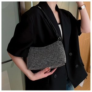 Detail of a sparkling rhinestone studded hobo bag on a model wearing a black blazer