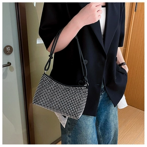 Detail of a sparkling rhinestone shoulder bag with black leather straps on a model