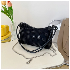 Detail of black rhinestone shoulder bag with silver chain and leather handle in a lifestyle setting
