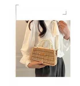 Detail of hand-woven straw bag featuring pearl handle and crossbody strap