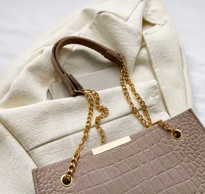 Detail of pink embossed crocodile tote with golden chain strap and comfortable handle