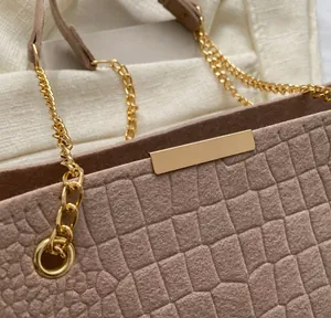 Macro shot of dusty pink crocodile pattern embossed texture and gold metal chain strap
