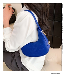 Close-up of bright blue hobo bag with crocodile pattern and elegant gold hardware details