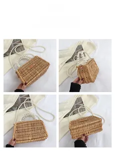 Detail view of woven straw handbag with large pearl handle and crossbody strap