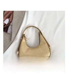 Detailed close-up of champagne gold crescent bag with luxury crocodile pattern texture