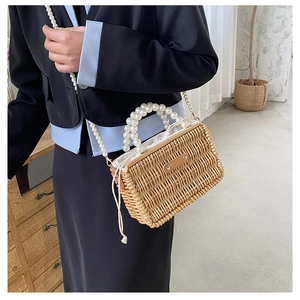 Detail of hand-woven straw bag featuring double pearl handle and white drawstring liner