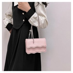 Detail of pink wave-edge handbag with silver metal chain and unique brand lettering