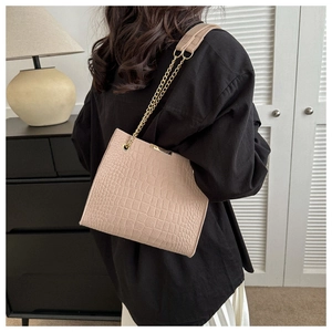 Detail of beige crocodile pattern tote bag with gold chain and fabric shoulder strap
