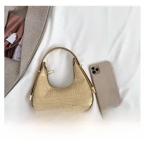 Golden crocodile texture crescent bag with size reference next to a mobile phone