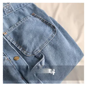 Detail of light blue denim tote with double orange stitching and metal button