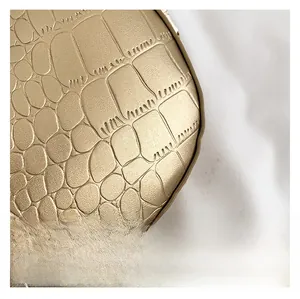 Detailed macro view of golden crocodile embossed texture and premium satin finish leather
