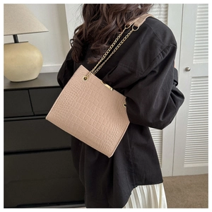 Detail of apricot crocodile-patterned felt tote bag with gold chain strap on shoulder