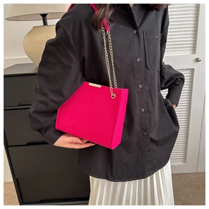 Detail of rose red crocodile embossed felt tote bag with elegant gold chain strap