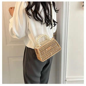 Detail of hand-woven straw bag with elegant faux pearl handle and pearl shoulder strap