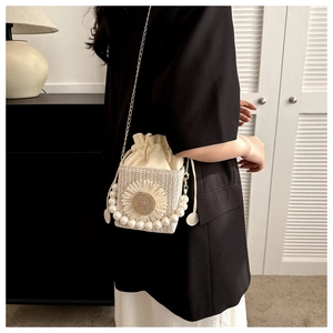 Detail of straw bucket bag with 3D daisy flower, pearl base trim and gold chain strap